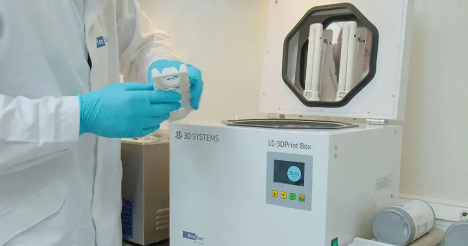 personne tenant une prothèse dentaire provenant d'une machine de post-traitement