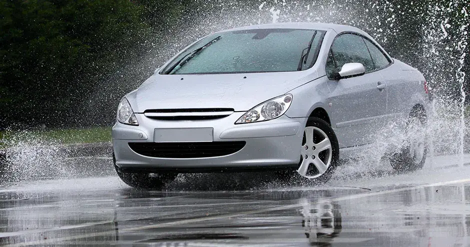 Une voiture qui traverse une flaque d'eau et crée une énorme éclaboussure.