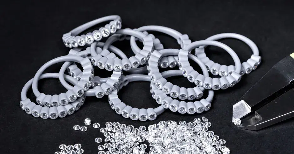 nombreuses bagues moulées en cire avec diamants incrustés, pied à coulisse tenant un diamant, diamants dispersés