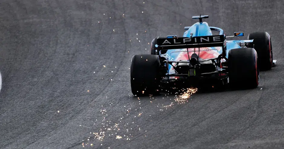 alpine f1 voiture de course sur le circuit en train de partir avec des étincelles sortant de l'arrière de la voiture
