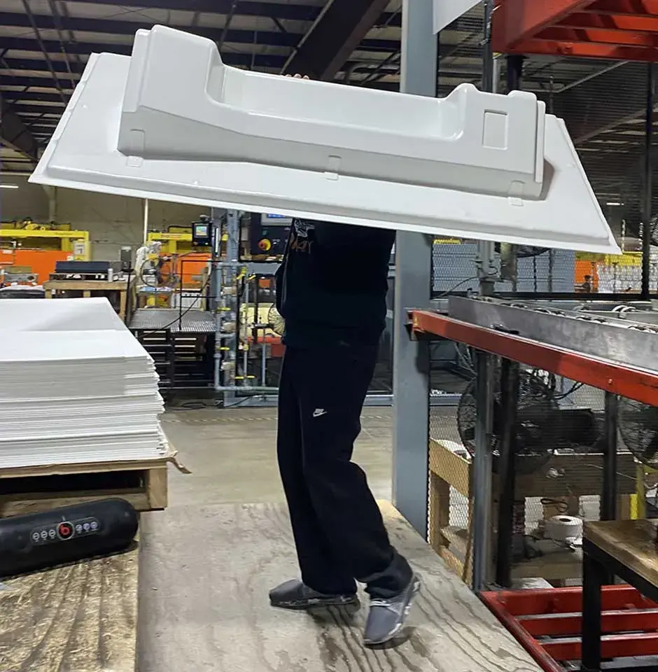 ouvrier portant une pièce thermoformée duo form