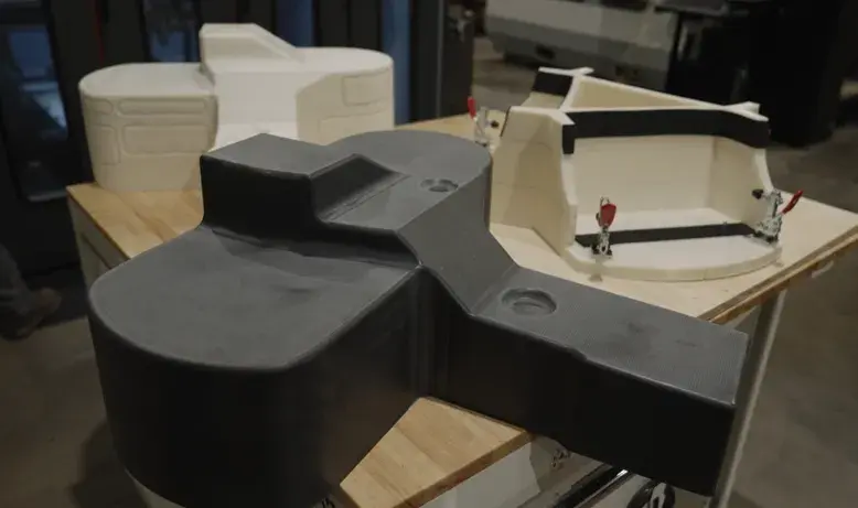 Un moule de thermoformage CF-PC imprimé en 3D et usiné, un prototype de pièce formée imprimé en ABS et un montage de garniture imprimé en ABS, tous produits sur le système à granulés EXT 1270 Titan de 3D Systems. 