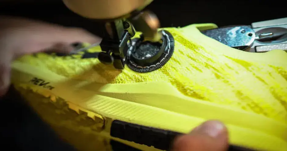 gros plan d'une chaussure jaune avec une pièce noire et ronde imprimée en 3D cousue sur celle-ci